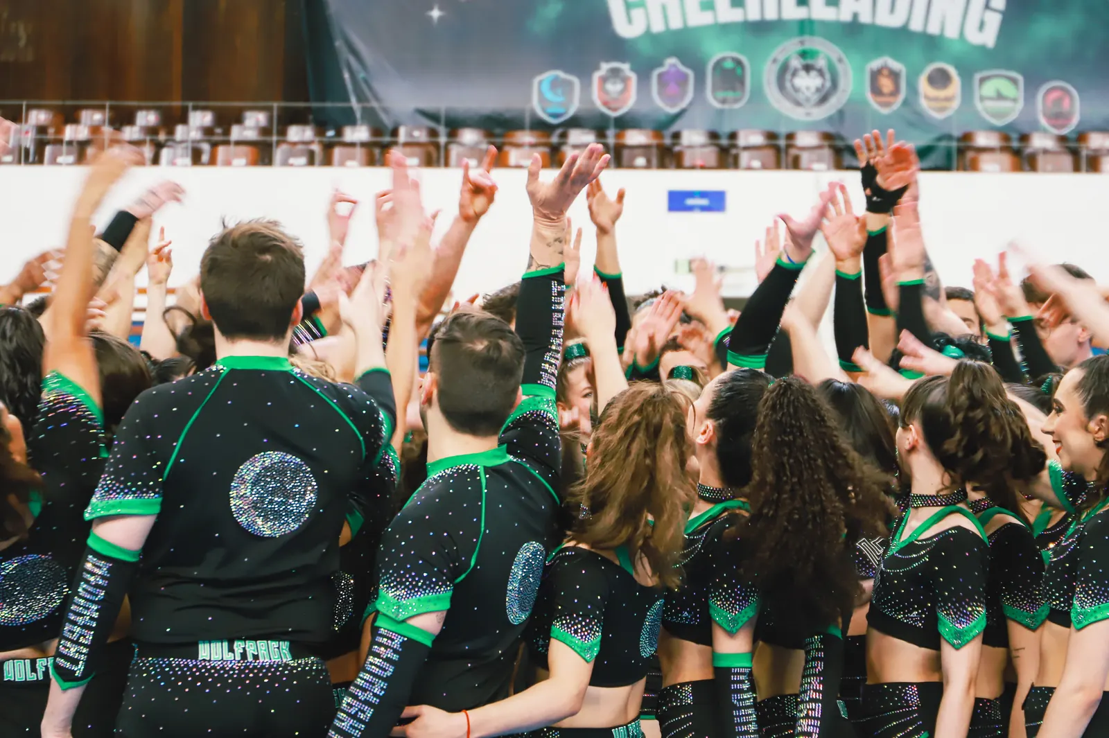 Atletas da Wolfpack reunidas de braços erguidos, diante do banner Wolfpack Cheerleading no Showcase 2025