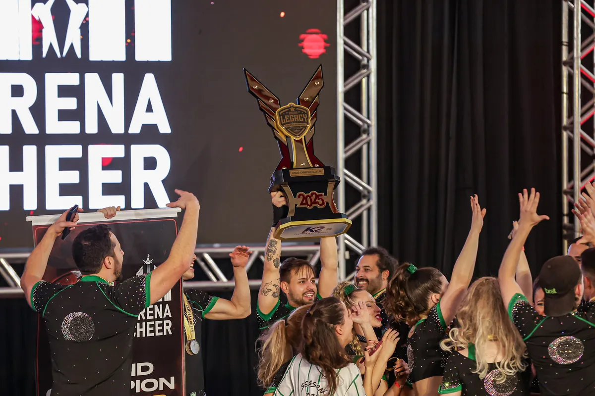 Atletas da Wolfpack comemorando com o troféu de Grand Champion no palco da Legacy 2025
