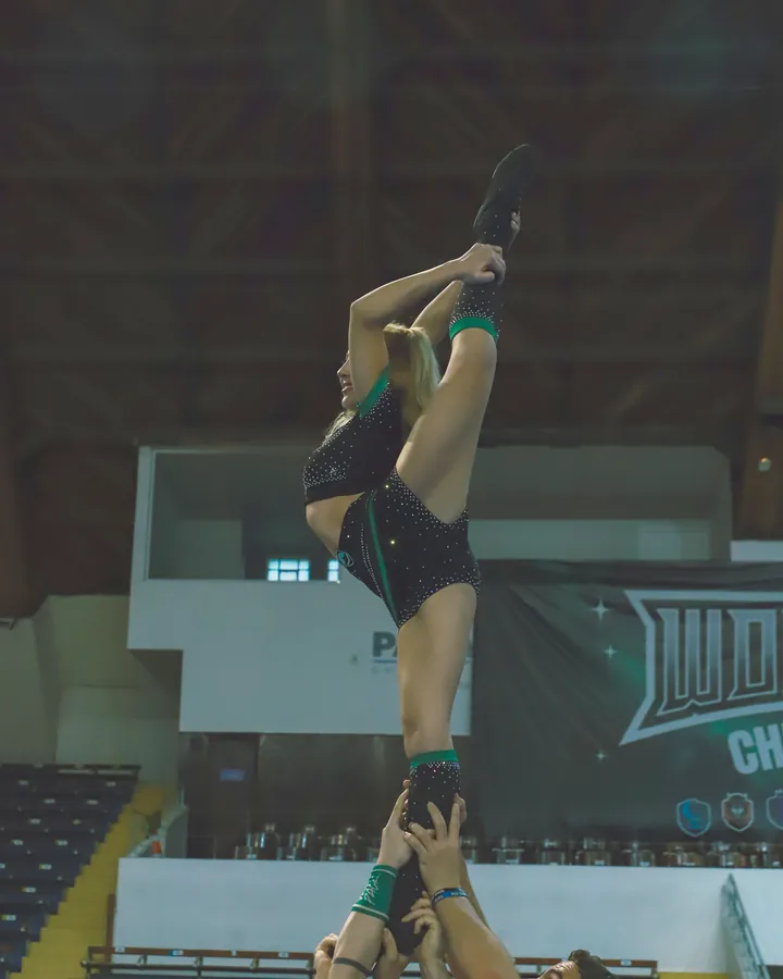 Flyer da Wolfpack com a perna estendida ao alto, sustentada pelas bases no Showcase 2025