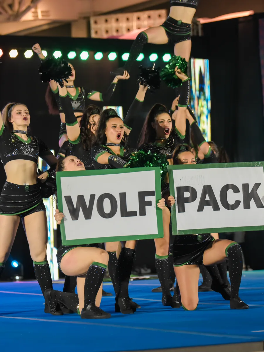 Atletas do Midnight, equipe universitária da Wolfpack, erguendo as placas WOLF e PACK no palco